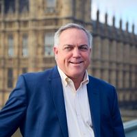 Dave Hynek from Business Fitness, Inc., with a confident smile, in front of the iconic Houses of Parliament in London.