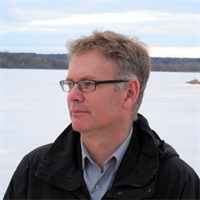 Kris Olds of the University of Wisconsin-Madison, captured in contemplative profile against a serene, icy lake backdrop.