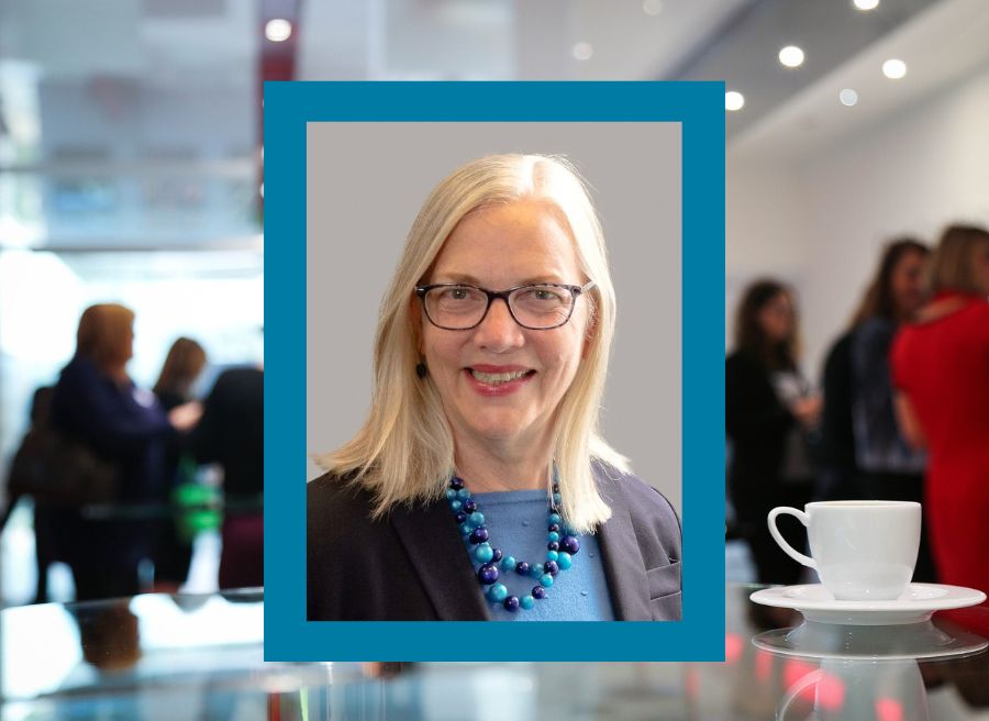 A photo of Margit Schatzman, President of ECE, smiling; conference attendees behind her