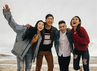 A group of South Korean students standing on a beach together laughing and enjoying themselves