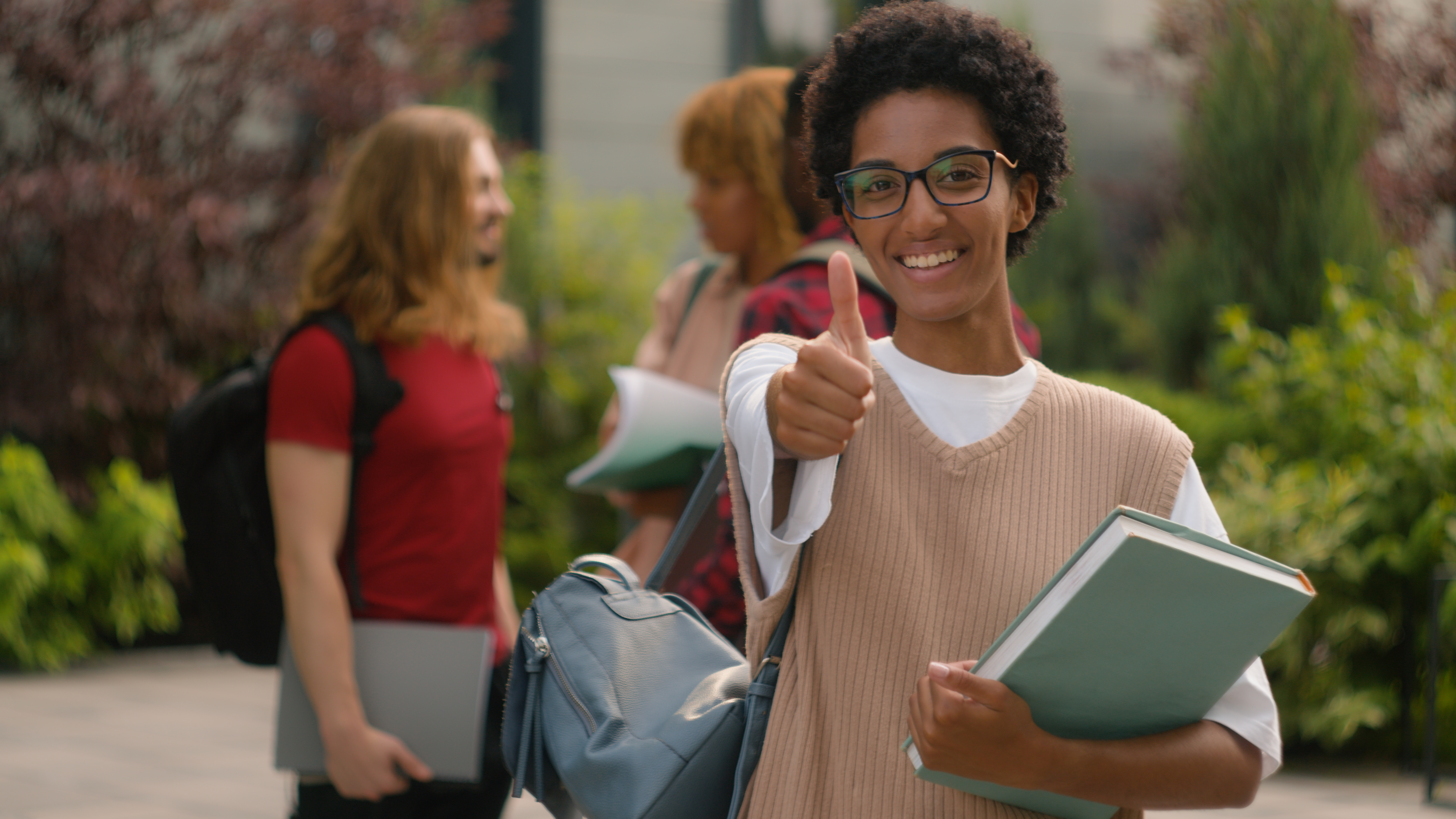 Smiling student giving thumbs up with backpack outdoors