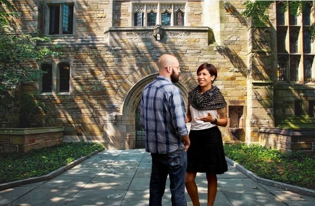 Two individuals speaking outside a college building