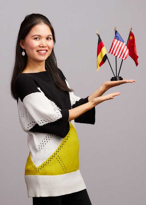 Jade Jiang Rieger holding a stand of various national flags including the American, German, and Chinese flags