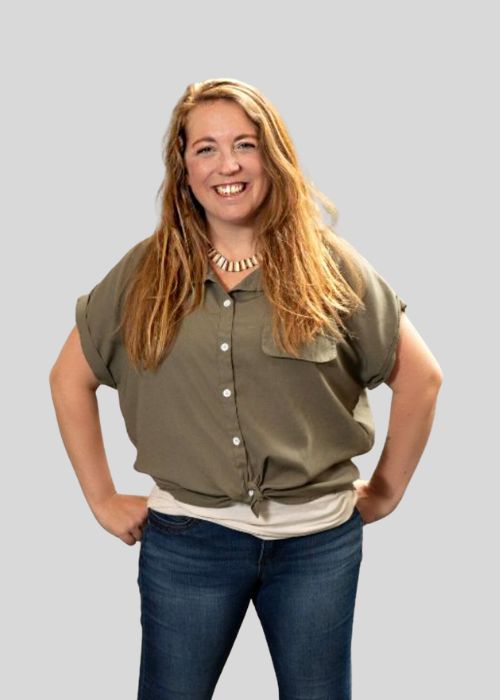 A friendly portrait of Kelsey Ward with hands on hips, sporting a green shirt and a stylish necklace.